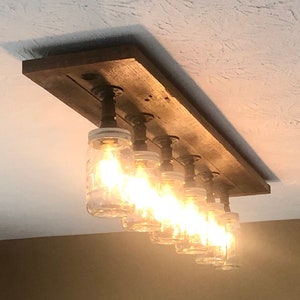 Pu&ograve; includere: Un lampadario rustico in legno per soffitto con sei luci in barattolo di muratore. Il lampadario &egrave; realizzato in legno riciclato e ha un design a tubo.