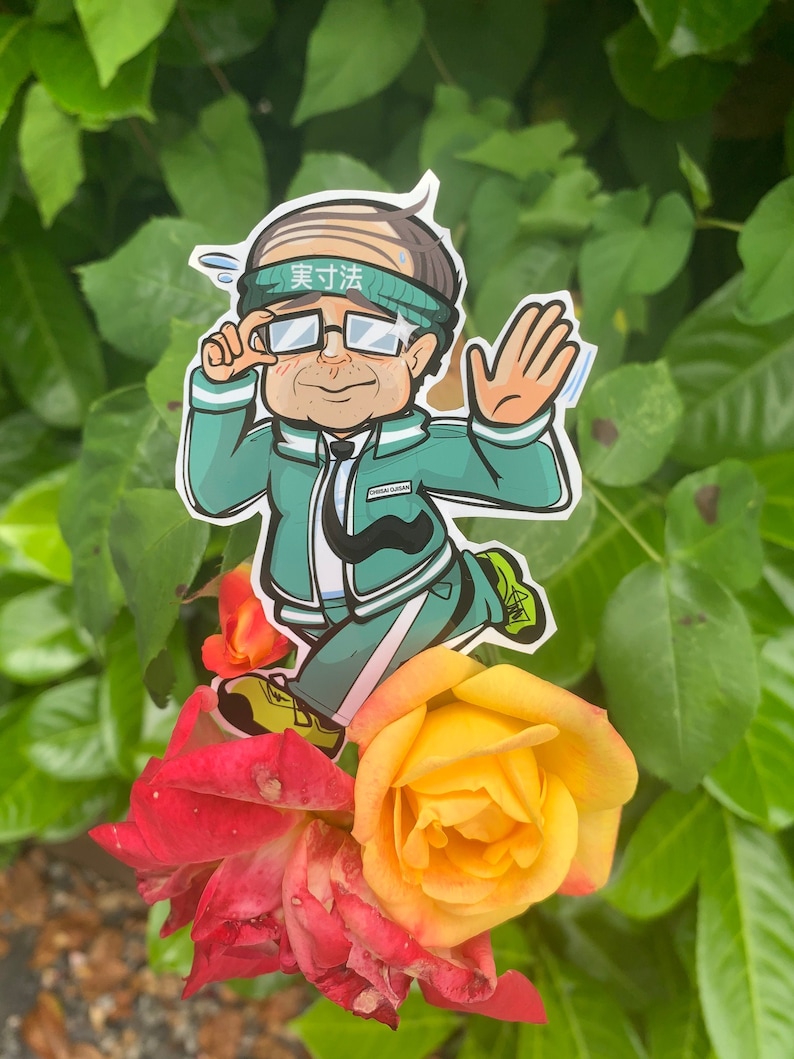 May include: A cartoon sticker of a person wearing a green jacket, white pants, and a headband that says "努力" in Japanese. The sticker is placed on top of a yellow and red rose.