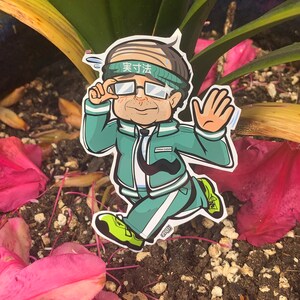 May include: A cartoon sticker of a person wearing a green jacket, white pants, and a headband that says "実力" in Japanese. The person is wearing glasses and has a mustache. The sticker is placed on a bed of pink flower petals.