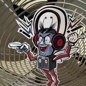 May include: A cartoon character with red headphones and a radio on its chest. The character is wearing red trousers and has a white and red wing. The character is pointing to the left and has a big smile. The background is a silver metal fan.