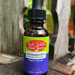 May include: A brown glass bottle with a black dropper top. The label is green, red, and white with the text "Red Turtle and the Plant Spirits Ashwagandha Withania somnifera Organic Tincture 30 ml/1 fluid oz."