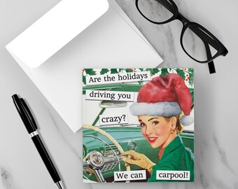 May include: A square greeting card with a retro image of a woman wearing a Santa hat driving a car. Text on the card reads "Are the holidays driving you crazy? We can carpool!" A white envelope, black pen, and glasses are also in the image.