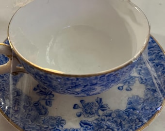 May include: A blue and white teacup and saucer set with a floral pattern and gold trim.