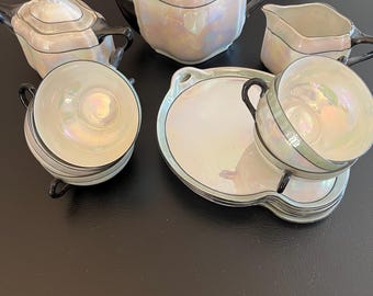 Puede incluir: Un juego de té vintage con un diseño blanco y negro. El juego incluye una tetera, una jarra de crema, un azucarero y dos tazas de té y platillos. Las tazas de té y los platillos tienen un acabado nacarado iridiscente.