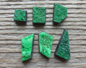 Puede incluir: Seis piezas geométricas pequeñas e irregulares con una superficie cristalina verde vibrante y texturizada y una base oscura y sólida. Estos componentes individuales presentan bordes angulares afilados y una capa superior rugosa y granular.