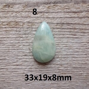 K&ouml;nnte beinhalten: Ein hellgr&uuml;ner, tropfenf&ouml;rmiger Edelstein mit wei&szlig;en Adern. Der Edelstein misst 33x19x8mm.