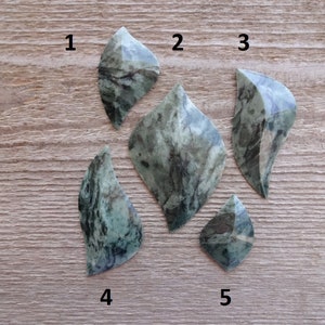 Puede incluir: Cinco formas de hojas de piedra marmoleada verde y negra, numeradas del 1 al 5.