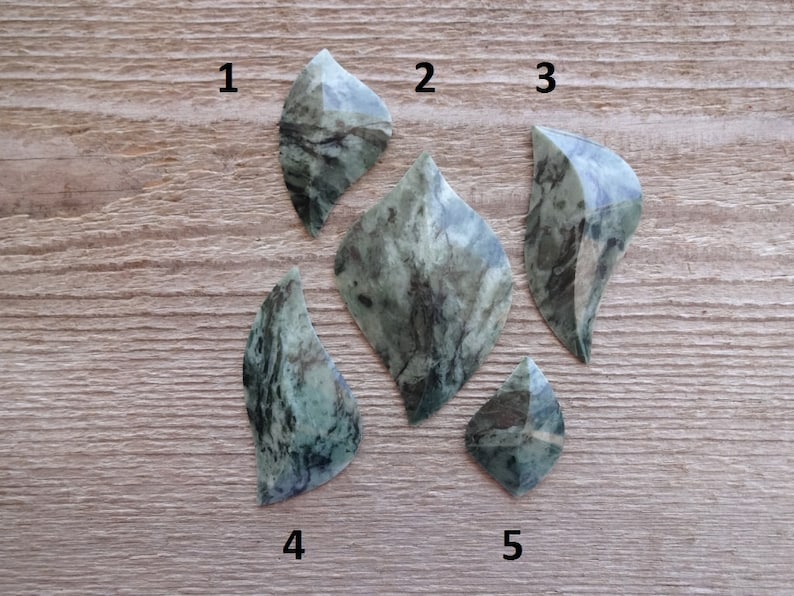 Puede incluir: Cinco formas de hojas de piedra marmoleada verde y negra, numeradas del 1 al 5.