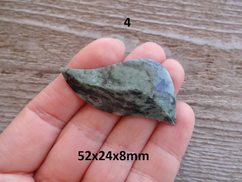 Puede incluir: Una piedra verde y negra con forma de hoja, que mide 52x24x8mm.