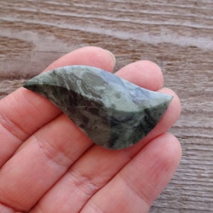Puede incluir: Una piedra verde y negra con una forma org&aacute;nica &uacute;nica. La piedra es lisa y pulida, con un patr&oacute;n de remolino de verde y negro.