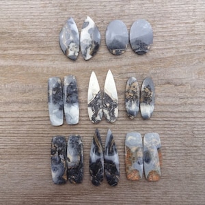 May include: A set of ten black and white agate cabochons, with various shapes and sizes. The cabochons are polished and have a natural, organic look.