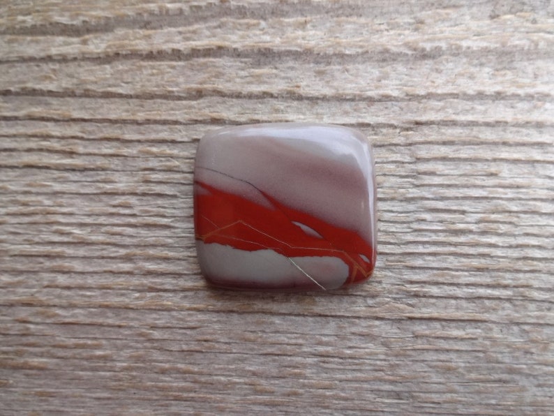 May include: A square, red, white, and gray agate cabochon with a unique pattern of veins and swirls.