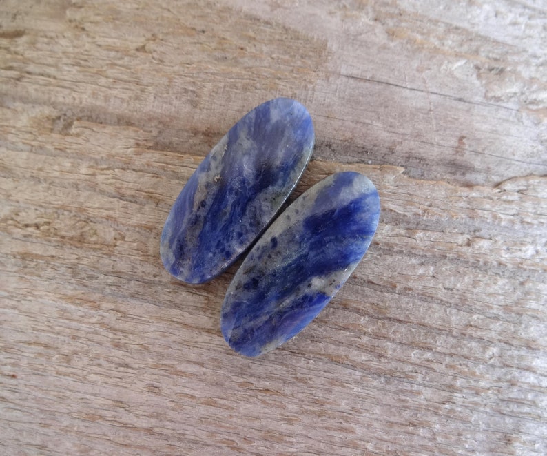 K&ouml;nnte beinhalten: Zwei ovale, blaue und wei&szlig;e Lapislazuli-Steine mit Marmorierung.