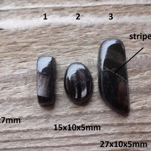 May include: Three black cabochon gemstones with a stripe pattern. The gemstones are labeled 1, 2, and 3. The measurements are 17x6x7mm, 15x10x5mm, and 27x10x5mm.
