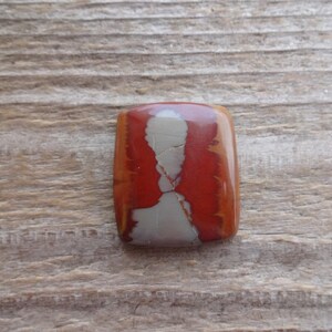 May include: A rectangular cabochon of red, white, and brown jasper with a swirling pattern.