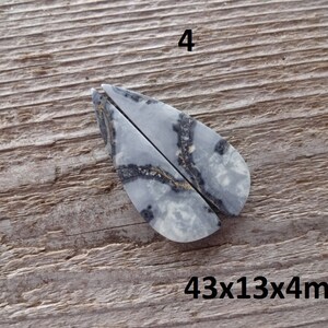 Puede incluir: Dos piedras pulidas en forma de l&aacute;grima, con un patr&oacute;n veteado gris y blanco y vetas negras. Las piedras se muestran sobre una superficie de madera. El texto "4" est&aacute; encima de las piedras y "43x13x4mm" debajo.