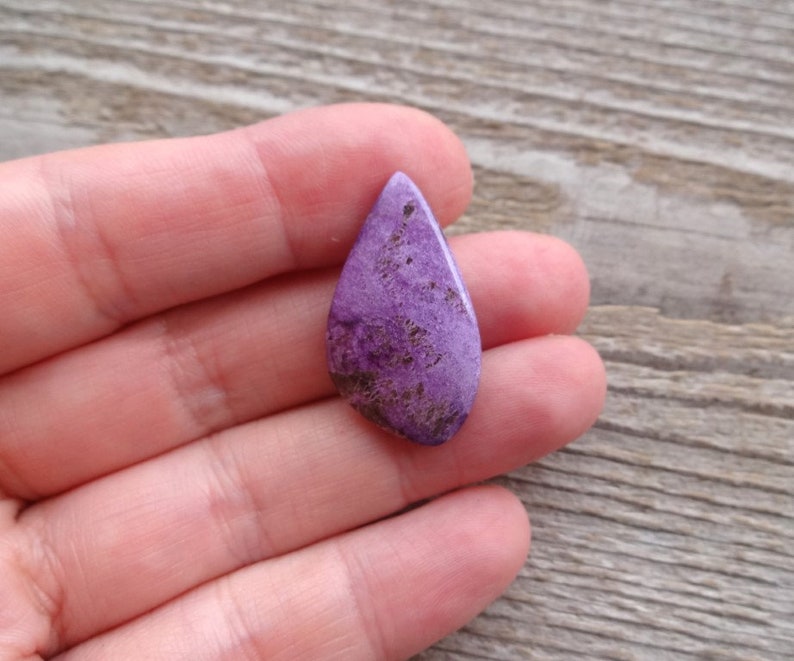 May include: A teardrop-shaped purple and brown gemstone cabochon.