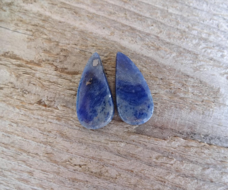 K&ouml;nnte beinhalten: Zwei tropfenf&ouml;rmige blaue Lapislazuli-Steine mit wei&szlig;en Adern.