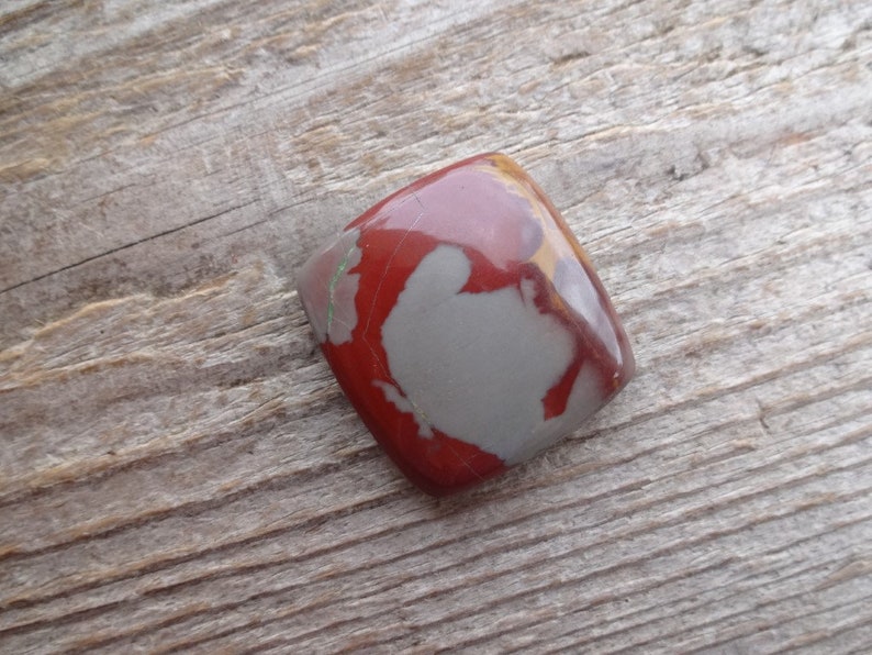 May include: A red, gray, and brown jasper cabochon with a square shape.