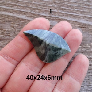 Puede incluir: Un cabuj&oacute;n de piedra verde y negro con forma curva. La piedra mide 40x24x6mm.