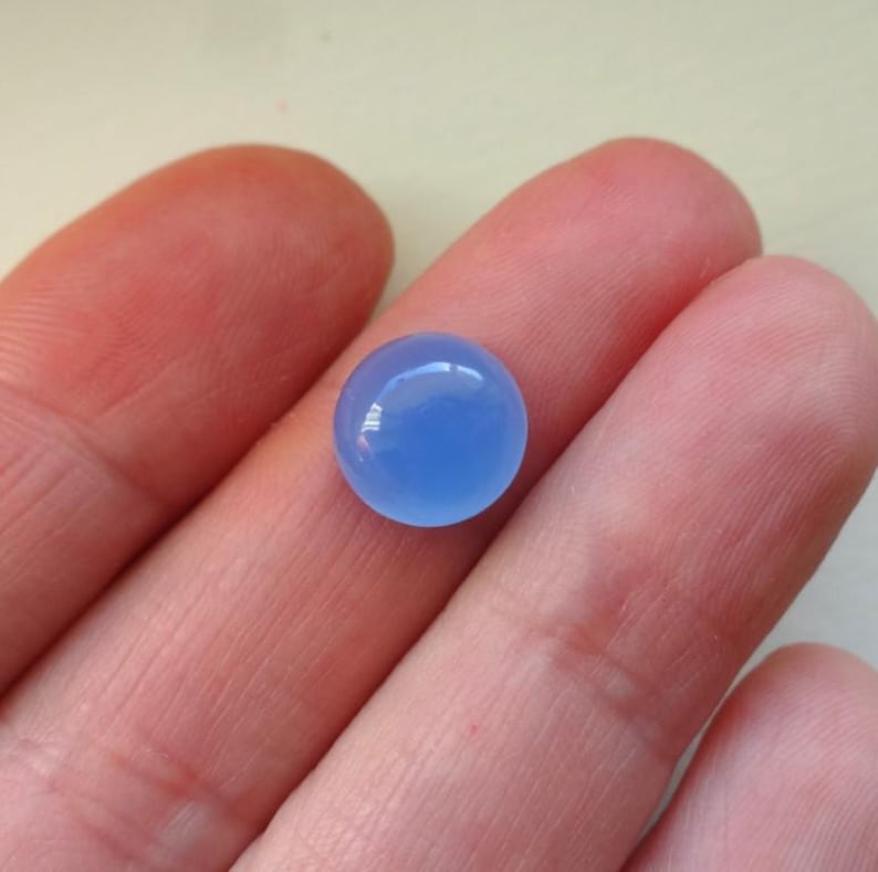 Puede incluir: Un cabuj&oacute;n redondo de piedra preciosa azul claro.