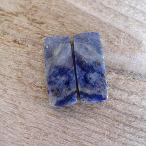K&ouml;nnte beinhalten: Zwei rechteckige St&uuml;cke aus blauem und wei&szlig;em Lapislazuli-Edelstein. Die Steine haben ein marmoriertes Muster und sind glatt und poliert.