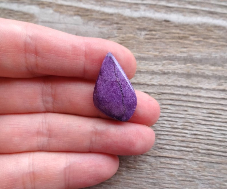 May include: A teardrop-shaped purple gemstone with white veins and a rough, natural finish.