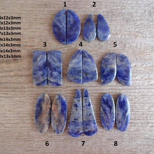 K&ouml;nnte beinhalten: Acht Paare blaue und wei&szlig;e Lapislazuli-Cabochons, geschnitten und poliert f&uuml;r die Schmuckherstellung. Die Cabochons haben verschiedene Formen, darunter oval, tropfenf&ouml;rmig und rechteckig. Die Gr&ouml;&szlig;en der Cabochons sind in Millimetern angegeben.