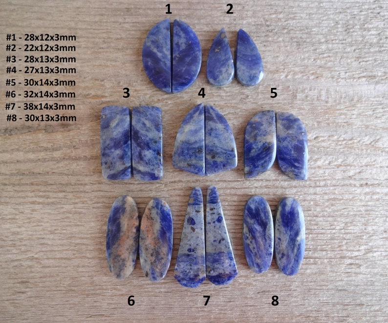K&ouml;nnte beinhalten: Acht Paare blaue und wei&szlig;e Lapislazuli-Cabochons, geschnitten und poliert f&uuml;r die Schmuckherstellung. Die Cabochons haben verschiedene Formen, darunter oval, tropfenf&ouml;rmig und rechteckig. Die Gr&ouml;&szlig;en der Cabochons sind in Millimetern angegeben.