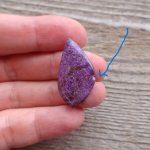 May include: Purple and silver teardrop shaped cabochon gemstone with a sparkly, iridescent finish.