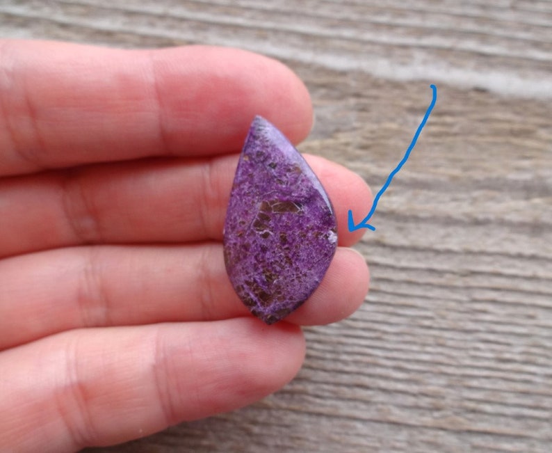 May include: Purple and silver teardrop shaped cabochon gemstone with a sparkly, iridescent finish.