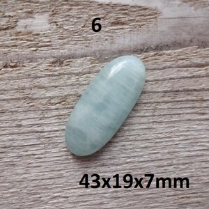 K&ouml;nnte beinhalten: Ein hellblauer ovaler Cabochon-Edelstein mit den Ma&szlig;en 43x19x7mm. Der Stein hat eine glatte, polierte Oberfl&auml;che und ein subtiles, wolkiges Muster.