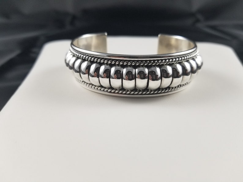 Op de afbeelding: Een zilveren armband met een kralenontwerp. De armband heeft een gladde, gepolijste afwerking en een eenvoudige, elegante stijl.