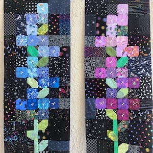 Puede incluir: Dos paneles de tela negra con diseños de patchwork coloridos. Cada panel presenta un diseño de flor estilizado con un tallo verde y pétalos coloridos. Los paneles están colgados en una pared.