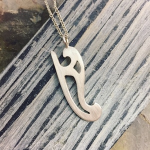 May include: A silver pendant necklace with a delicate, openwork design. The pendant is shaped like a stylized letter 'S' with a flowing, organic form.