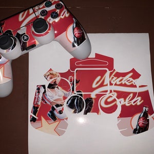 May include: A white sticker sheet with a cutout design of a PlayStation controller. The design features a red and white background with a woman in a white and black outfit, a bottle of Nuka-Cola, and the text "Nuka-Cola".