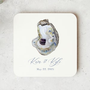 May include: A white square coaster with a watercolor illustration of an oyster shell. The text "Kara & Kyle" and "May 22, 2021" is printed in blue ink.
