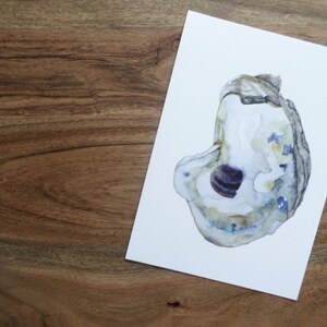 May include: Watercolor painting of an oyster shell with a purple and white interior. The shell is painted in shades of blue, green, and brown.