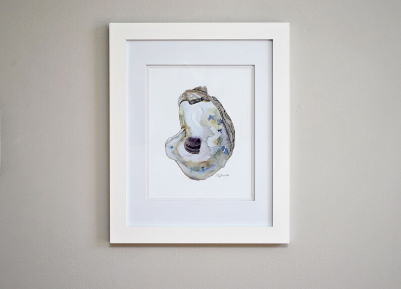 May include: A framed watercolor painting of an oyster shell with a purple interior. The shell is painted in shades of blue, green, and brown. The painting is signed by the artist.