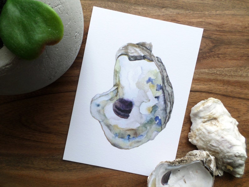 May include: A watercolor painting of an oyster shell with a purple interior. The shell is painted in shades of blue, green, and brown.