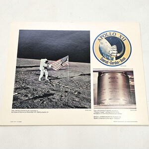 May include: A vintage print featuring the Apollo 12 mission. The image shows an astronaut planting the American flag on the moon. The print also includes the Apollo 12 mission logo and a commemorative plaque.