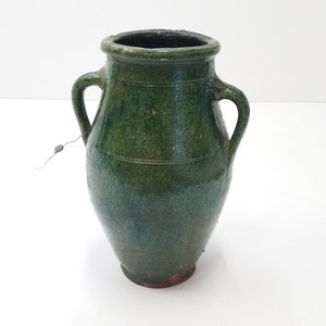 May include: A green glazed ceramic pitcher with two handles. The pitcher has a rounded body and a wide mouth.