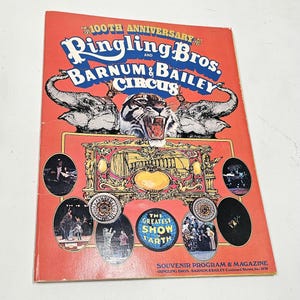 May include: A 1970 Ringling Bros. and Barnum & Bailey Circus 100th Anniversary souvenir program and magazine. The red cover features a tiger, two elephants, a golden circus wagon, and the text The Greatest Show on Earth with various photos.