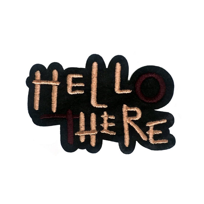 May include: A black embroidered patch with the words "HELLO THERE" in tan thread. The patch has a dark maroon accent and a black border, ideal for adding to clothing or accessories.