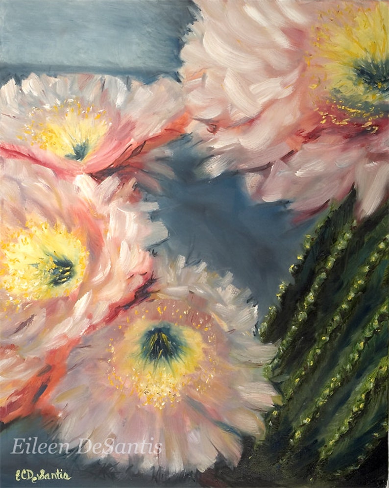 May include: An oil painting depicting several pale pink cactus flowers with yellow centres and a green cactus stem. The painting has a soft, impressionistic style with visible brushstrokes. The artist's signature, "Eileen DeSantis," is in the bottom left corner.