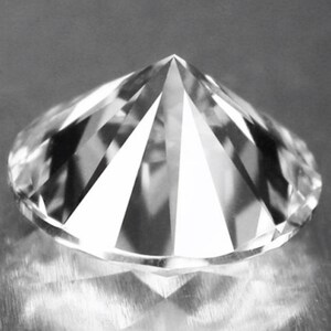 May include: A clear, round, faceted diamond with a pointed top.