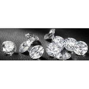 May include: A group of round, clear, sparkling diamonds on a black surface.