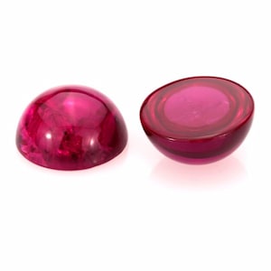 以下が含まれることがあります： 2つの丸いピンクのcabochon宝石。宝石は滑らかで光沢があります