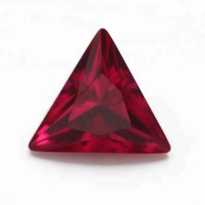 May include: A deep red triangular gemstone with a faceted cut.