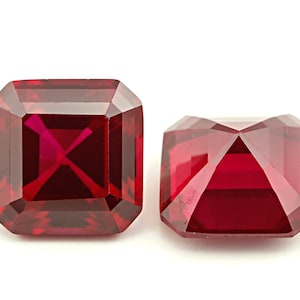 May include: Two deep red square-shaped gemstones with a faceted cut.